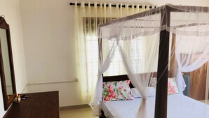 A bedroom with a four-poster bed, a bedside table, and a mirror. - Padmi Villa (Weligama)