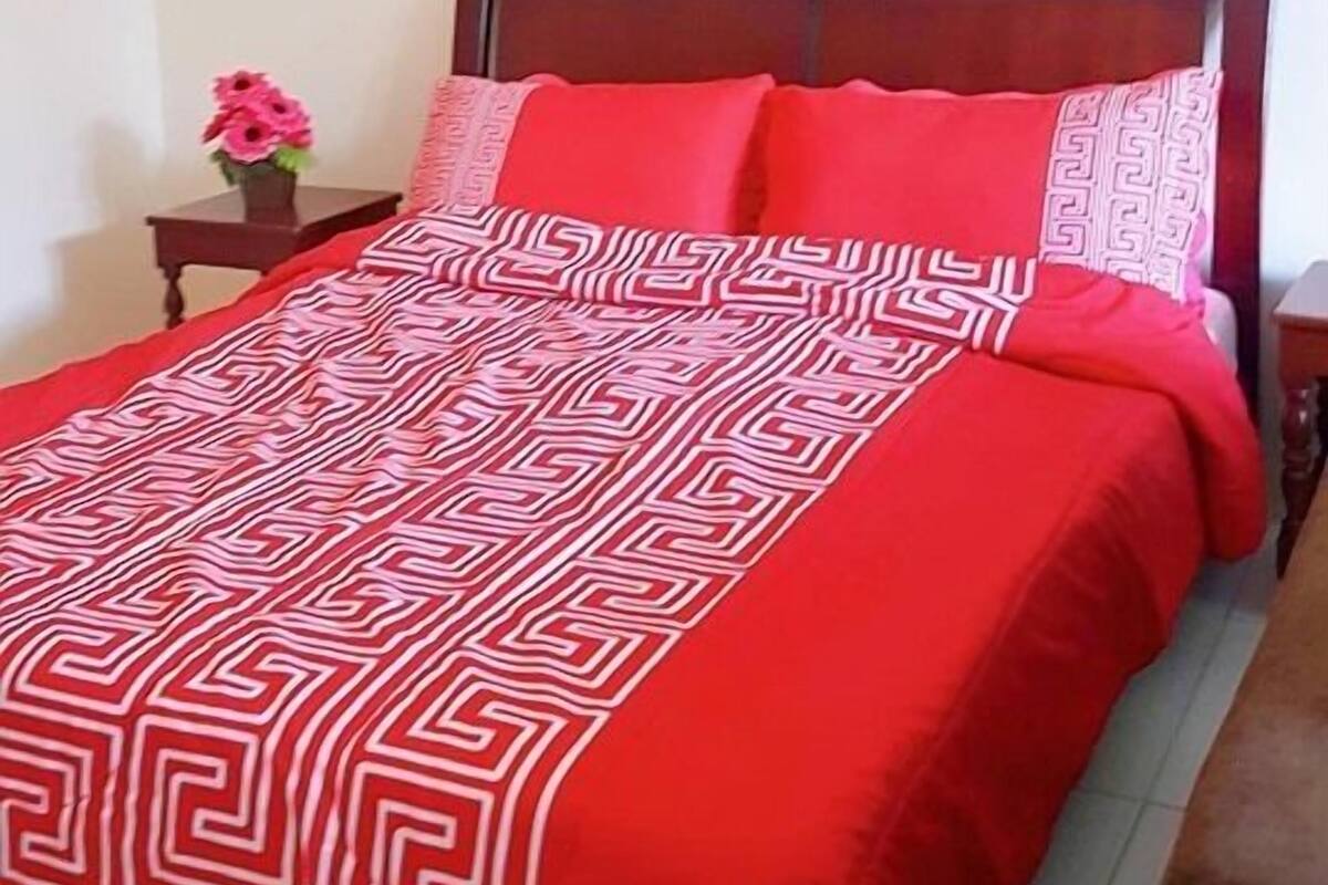 A bedroom with a bed, a nightstand, and two framed pictures on the wall.