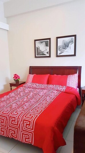 Un dormitorio con cama, mesita de noche y dos cuadros en la pared.