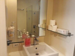 Un baño con lavabo, espejo y repisas con artículos de tocador.