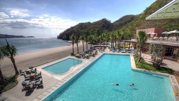 A swimming pool with lounge chairs and a view of the beach.