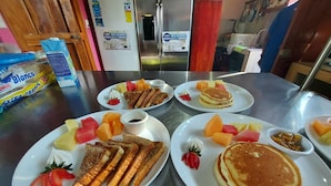 Un buffet de petit-déjeuner proposant divers plats, notamment des crêpes, des toasts et des fruits.
