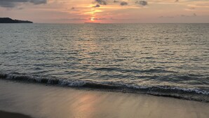 Une plage avec un coucher de soleil sur l’océan.