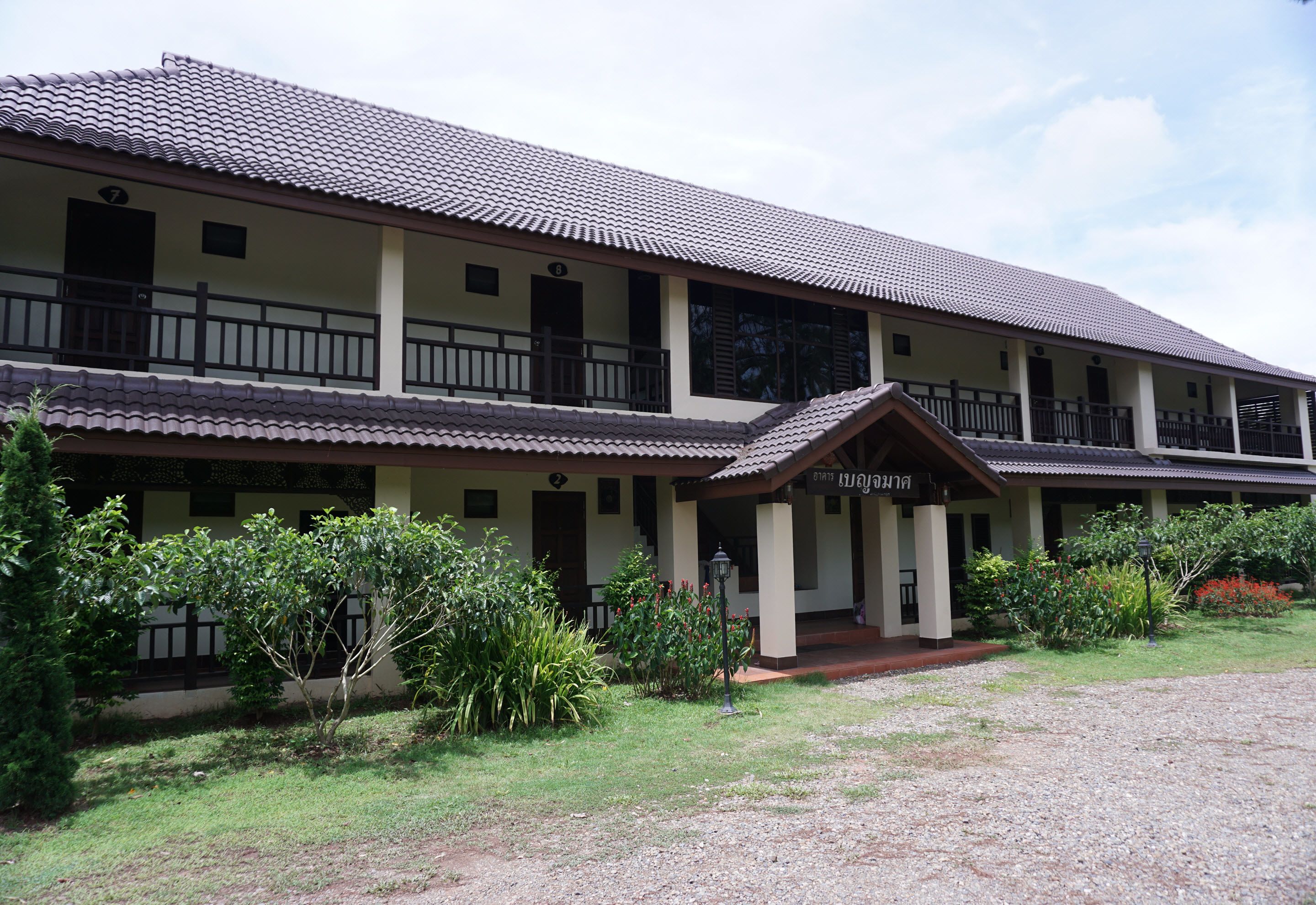 A two-story building with a tiled roof, multiple balconies, and a covered entrance.
