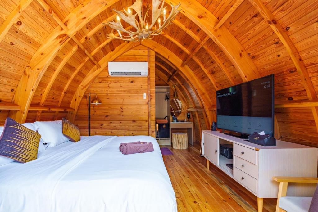 A cozy wooden room with a bed, a flat-screen TV, and a desk.