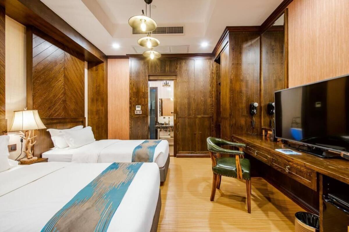 Une chambre d’hôtel avec deux lits, une télévision, un bureau et une chaise.