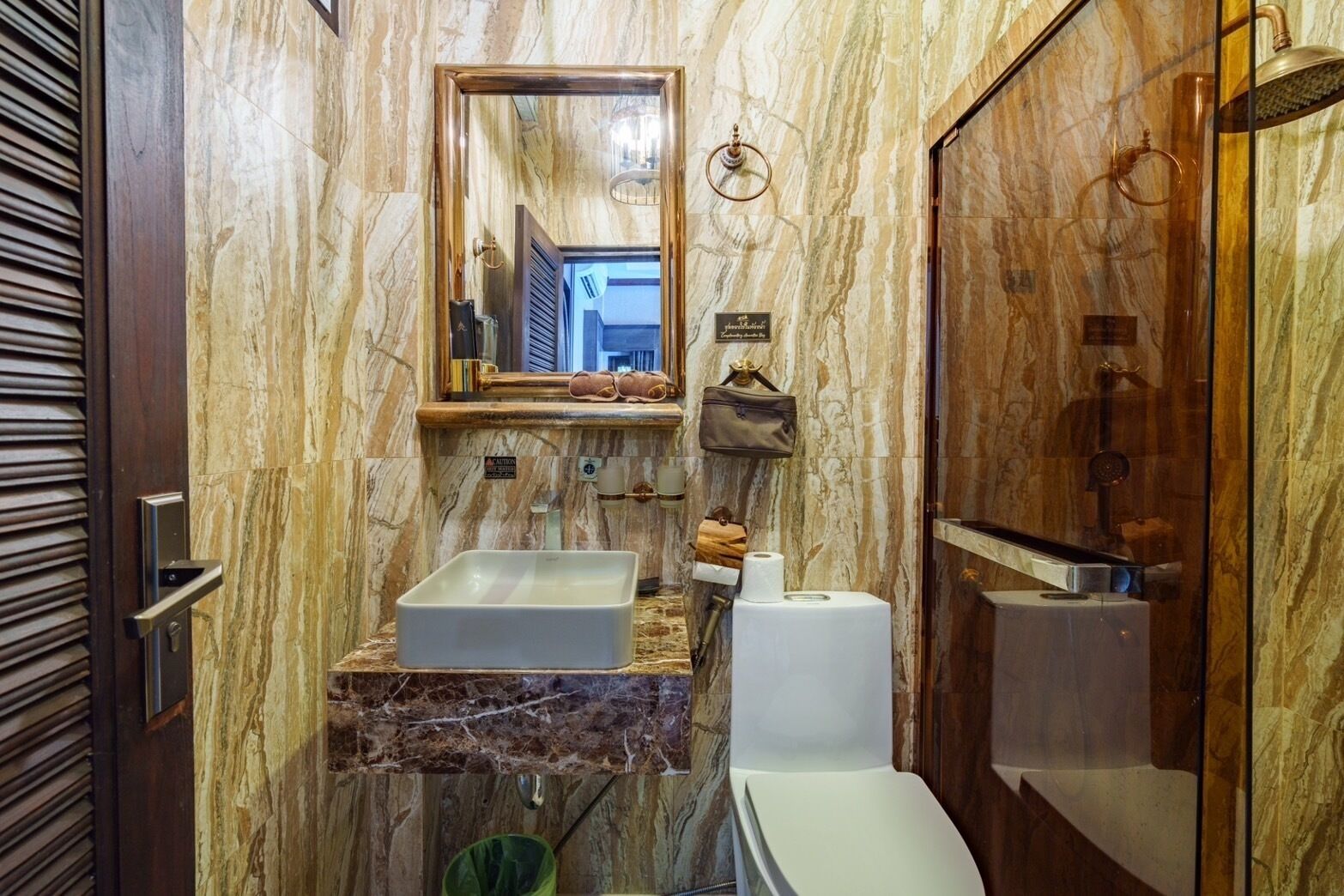 Uma casa de banho com toucador de mármore, lavatório, sanita e chuveiro.