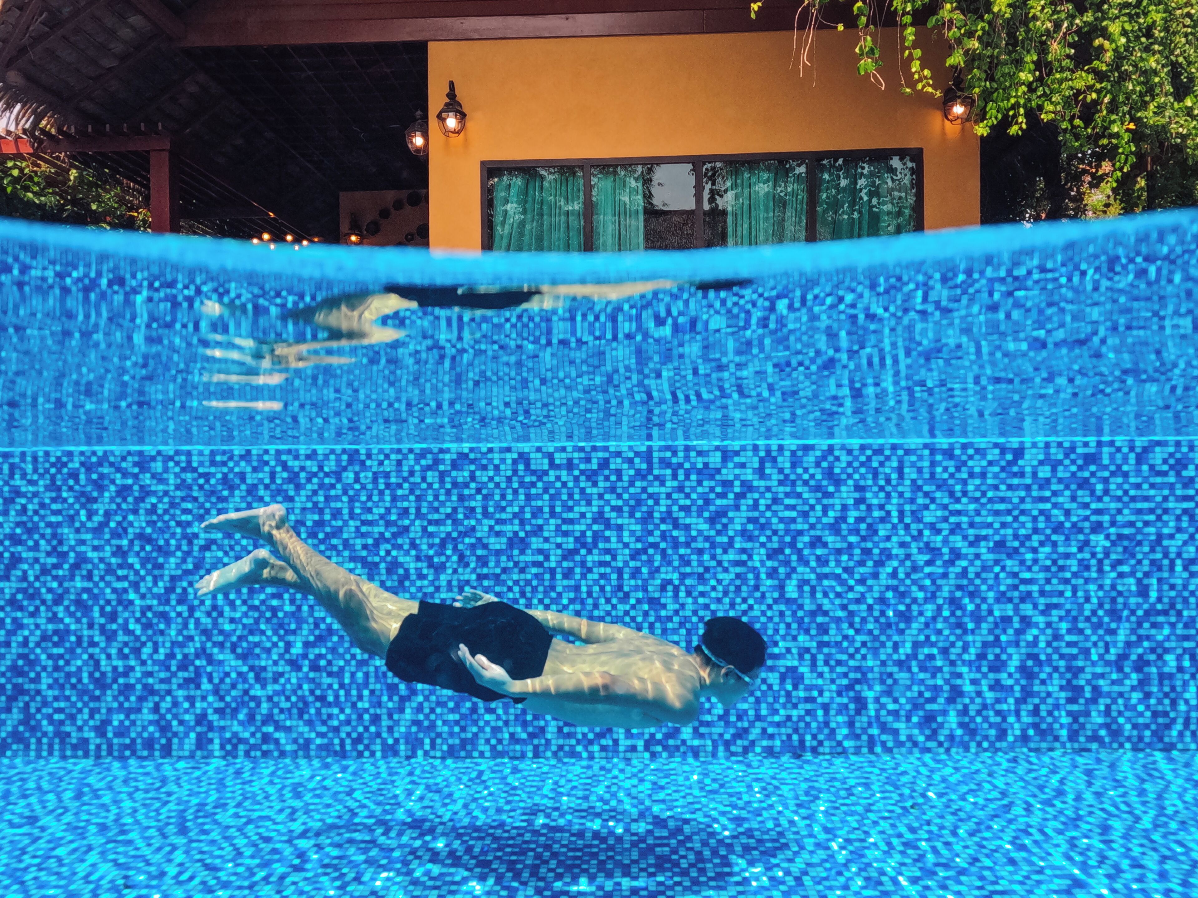 An underwater view of a swimming pool with a person swimming.