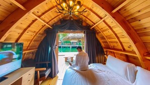 Ein holzgetäfelter Raum mit einem Bett, einem Fernseher und einem Fenster mit Vorhängen.