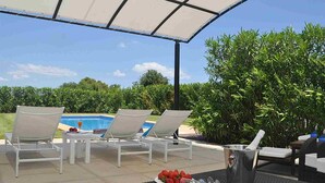 An outdoor lounge area with white lounge chairs, a pool, and a table with a fruit bowl and glasses. - Villa close to Rafa Nadal Center in Manacor (Manacor)