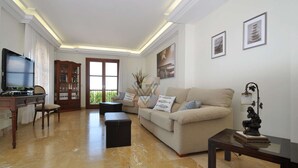 A spacious living room with a beige sofa, a television, a wooden cabinet, and a balcony with a view. - Villa close to Rafa Nadal Center in Manacor (Manacor)