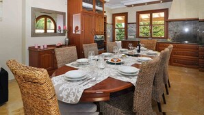 A dining area with a round table set for six, surrounded by wicker chairs. There is a kitchen area with wooden cabinets and a large window. - Villa close to Rafa Nadal Center in Manacor (Manacor)