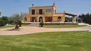 A two-story Mediterranean-style house with a stone facade, a balcony, and a well-maintained lawn. - Villa close to Rafa Nadal Center in Manacor (Manacor)