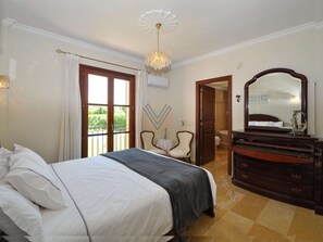 A bedroom with a large bed, a dresser, a mirror, and a door leading to a bathroom. - Villa close to Rafa Nadal Center in Manacor (Manacor)