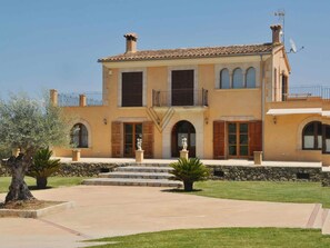 A two-story Mediterranean-style house with a stone facade, a central entrance with a statue, and a small balcony on the upper floor. - Villa close to Rafa Nadal Center in Manacor (Manacor)
