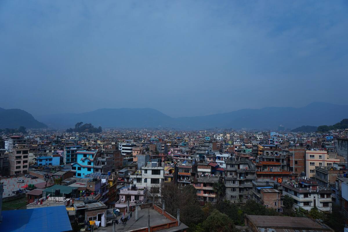Área urbana densamente povoada, com diversos estilos e cores de construções, incluindo estruturas azuis e brancas, sob um céu limpo.