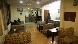 A hotel lobby with patterned sofas, wooden tables, and a reception desk. - Hotel Holy Temple Tree & Chautari Cafe (Kathmandu)