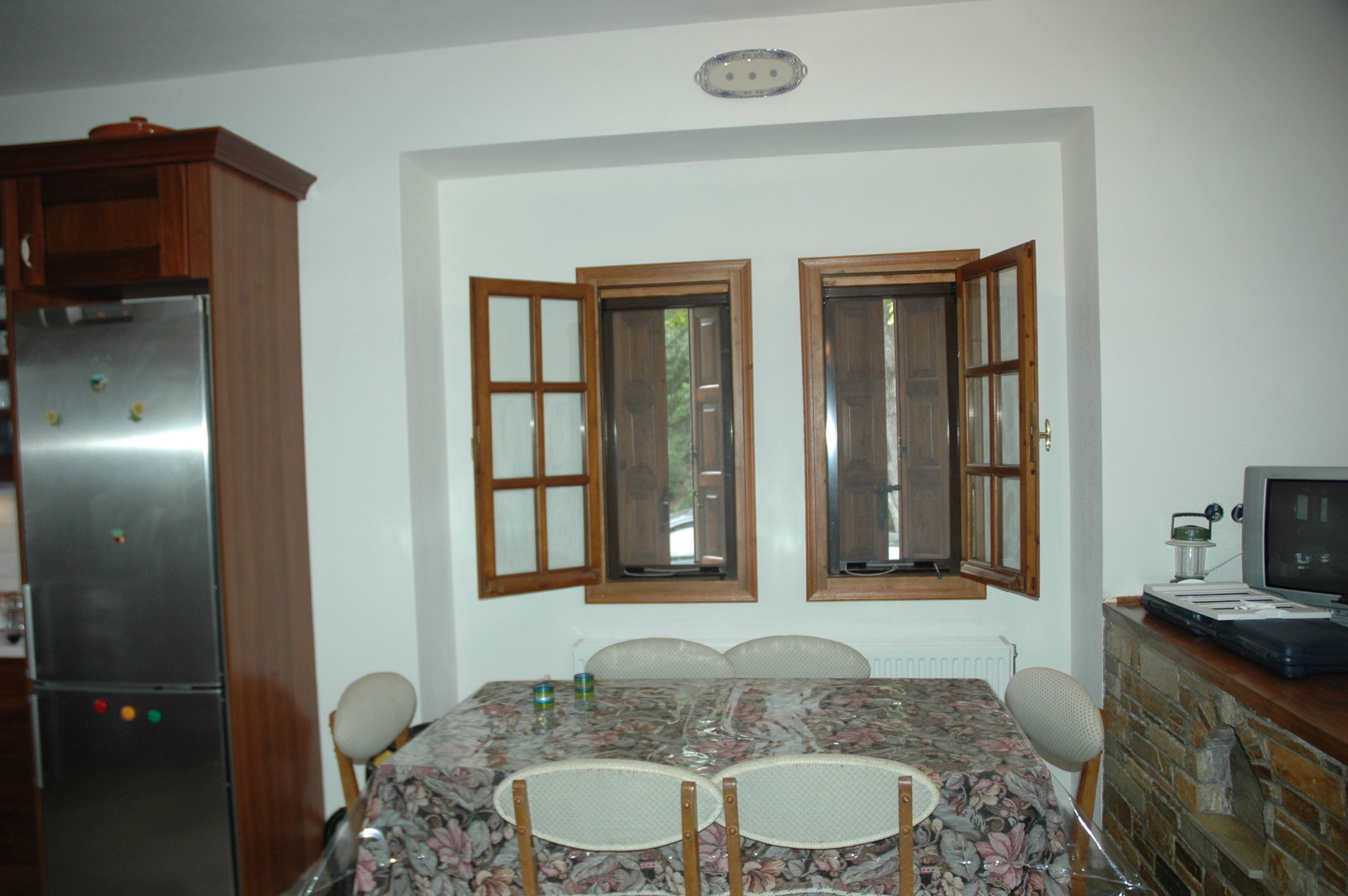 A dining area with a table, chairs, a refrigerator, and a television.