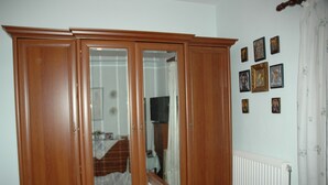 Ein Holzkleiderschrank mit Spiegelüren, ein Heizkörper und eine Wand mit gerahmten Bildern.