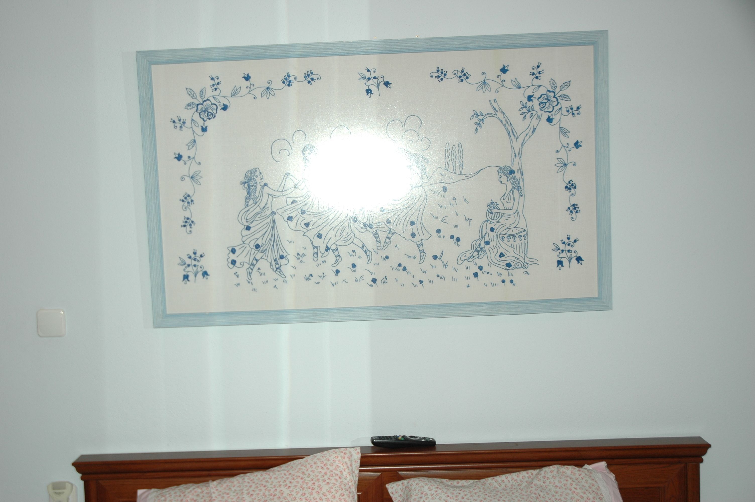 Une œuvre d’art encadrée, représentant des motifs floraux et des arbres, est accrochée au mur.