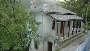 Ein zweistöckiges Gebäude mit einem Ziegeldach, einer Veranda mit Holzsäulen und einem kleinen Balkon.