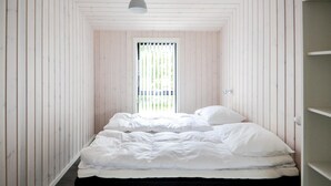 Una habitación estrecha con paneles de madera y una cama al fondo.