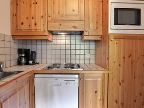 Une cuisine avec des meubles en bois, une cuisinière à gaz, un four à micro-ondes et un lave-vaisselle.