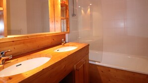A wooden bathroom with two sinks, a mirror, and a shower.