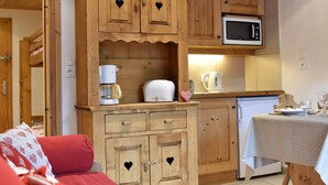 A cozy kitchen with wooden cabinets, a microwave, a coffee maker, and a table set for dining.
