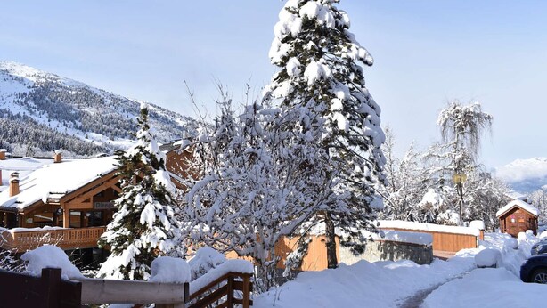 A snow-covered mountain village with wooden buildings and a clear sky.