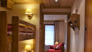 A cozy room with wooden bunk beds, a red sofa, and a window with curtains.