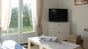 Ein Zimmer mit Fernseher auf einem Schrank, einem Tisch mit Gläsern und einem Fenster mit Vorhängen.