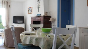 Ein Essbereich mit einem Tisch für zwei Personen, einem Fernseher, einem Kamin und einer blauen Tür.