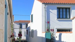 A narrow street with white buildings, red-tiled roofs, and a blue door.