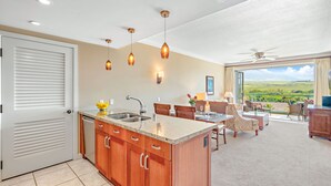 Una cocina moderna con una isla central, un comedor con vistas y un ventilador de techo.