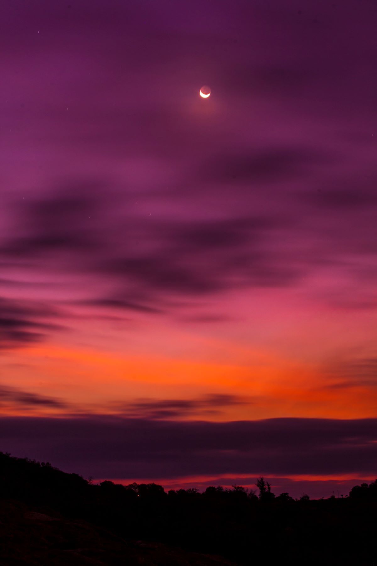 A night sky with a crescent moon and a sunset.