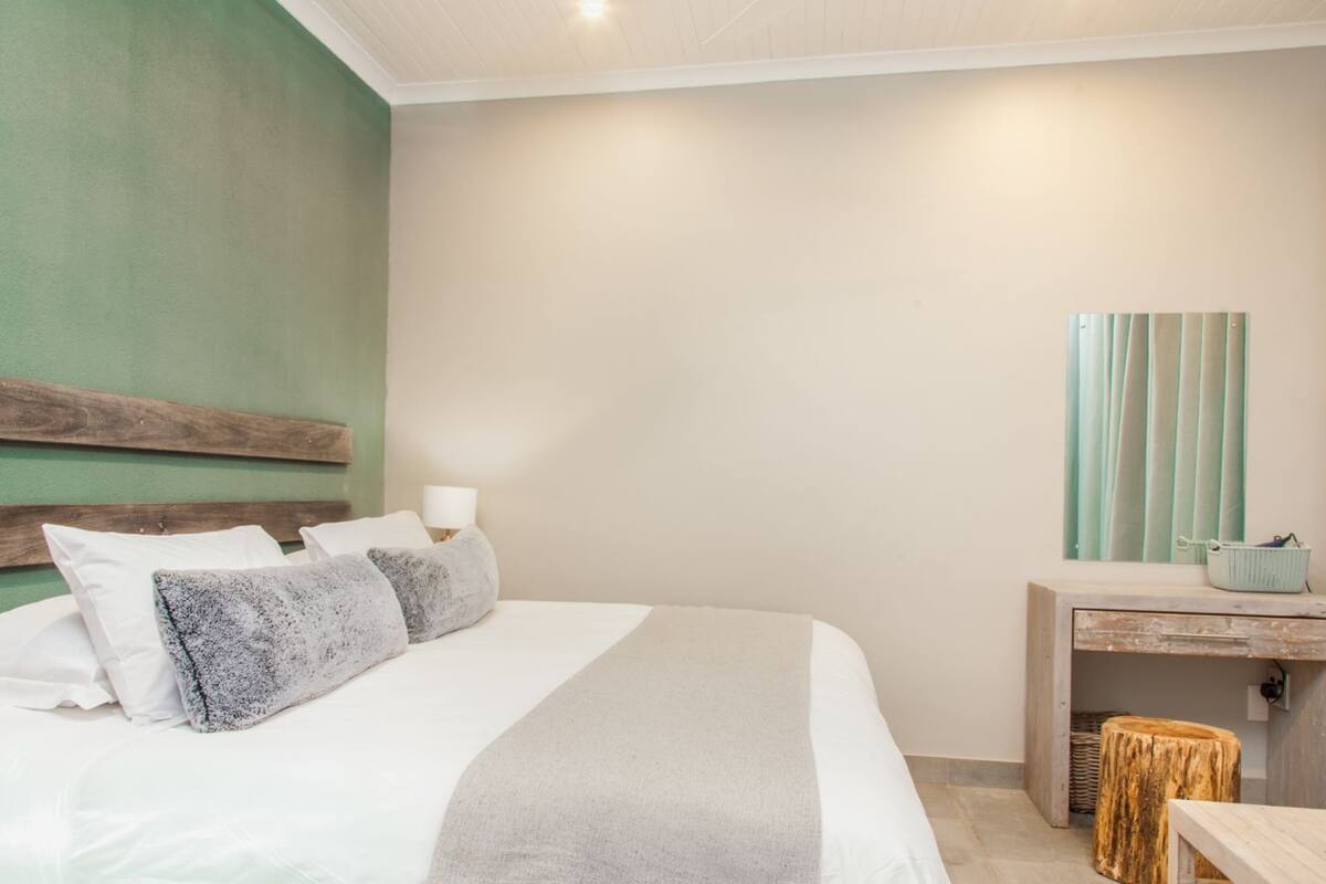 A neatly arranged bedroom with a bed, bedside table, and a mirror.
