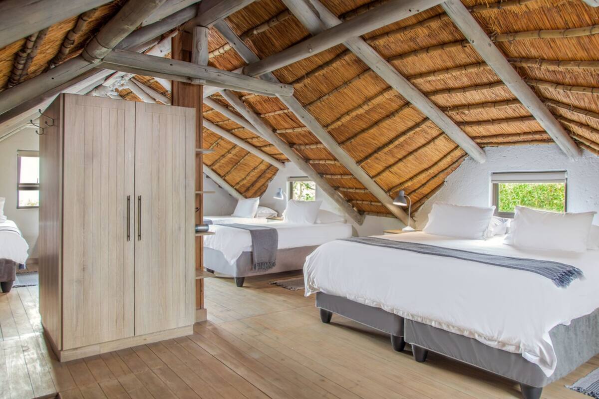 A high-ceilinged room with a thatched roof, wooden floors, and a large wardrobe.