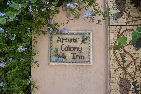 Une enseigne pour l’hôtel « Artists’ Colony Inn », ornée d’une mosaïque et portant un numéro de téléphone.