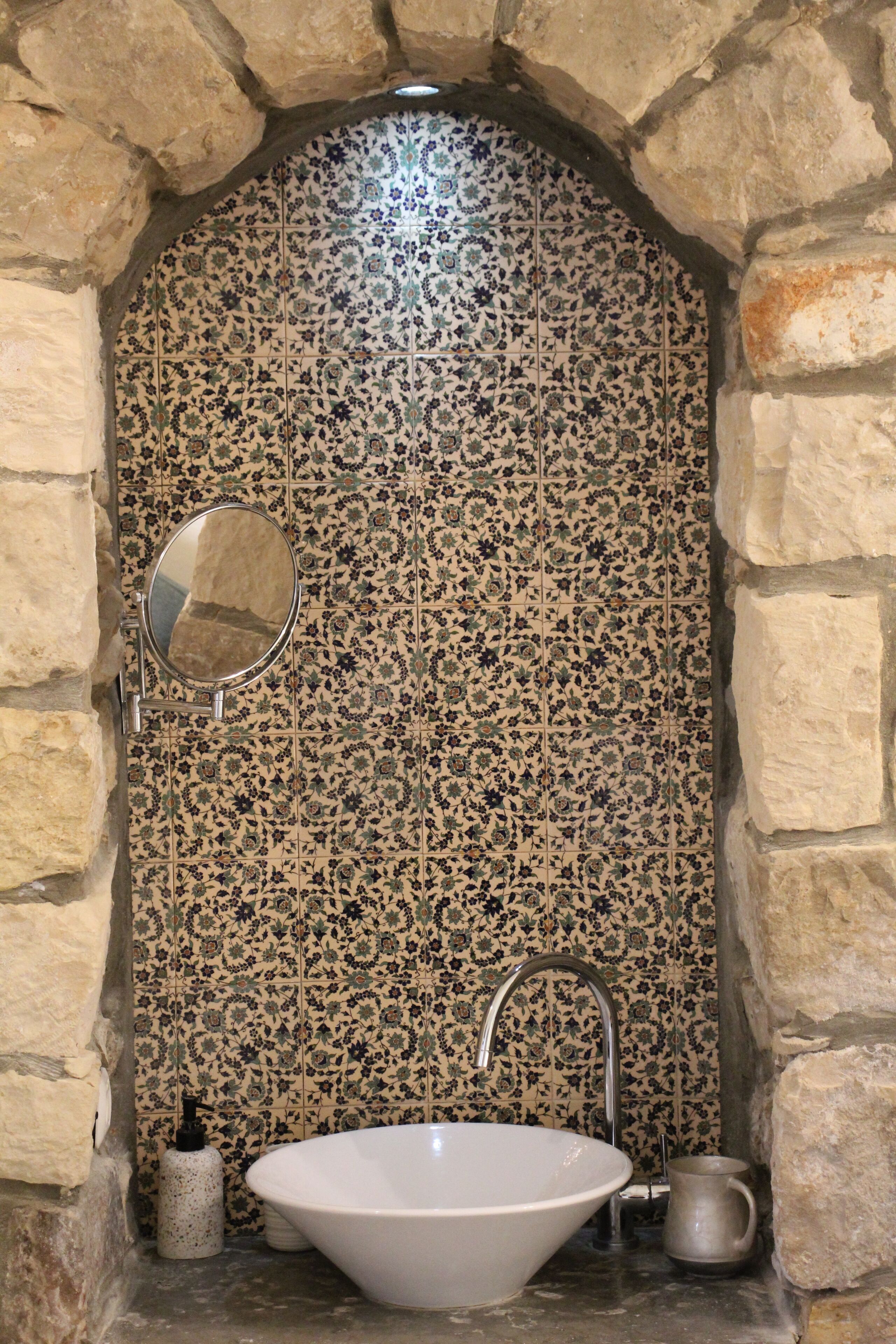 Casa de banho com lavatório independente, espelho e painel de azulejos.
