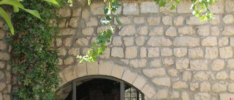 A stone building with an arched entrance, a potted plant, and a sign on the door.