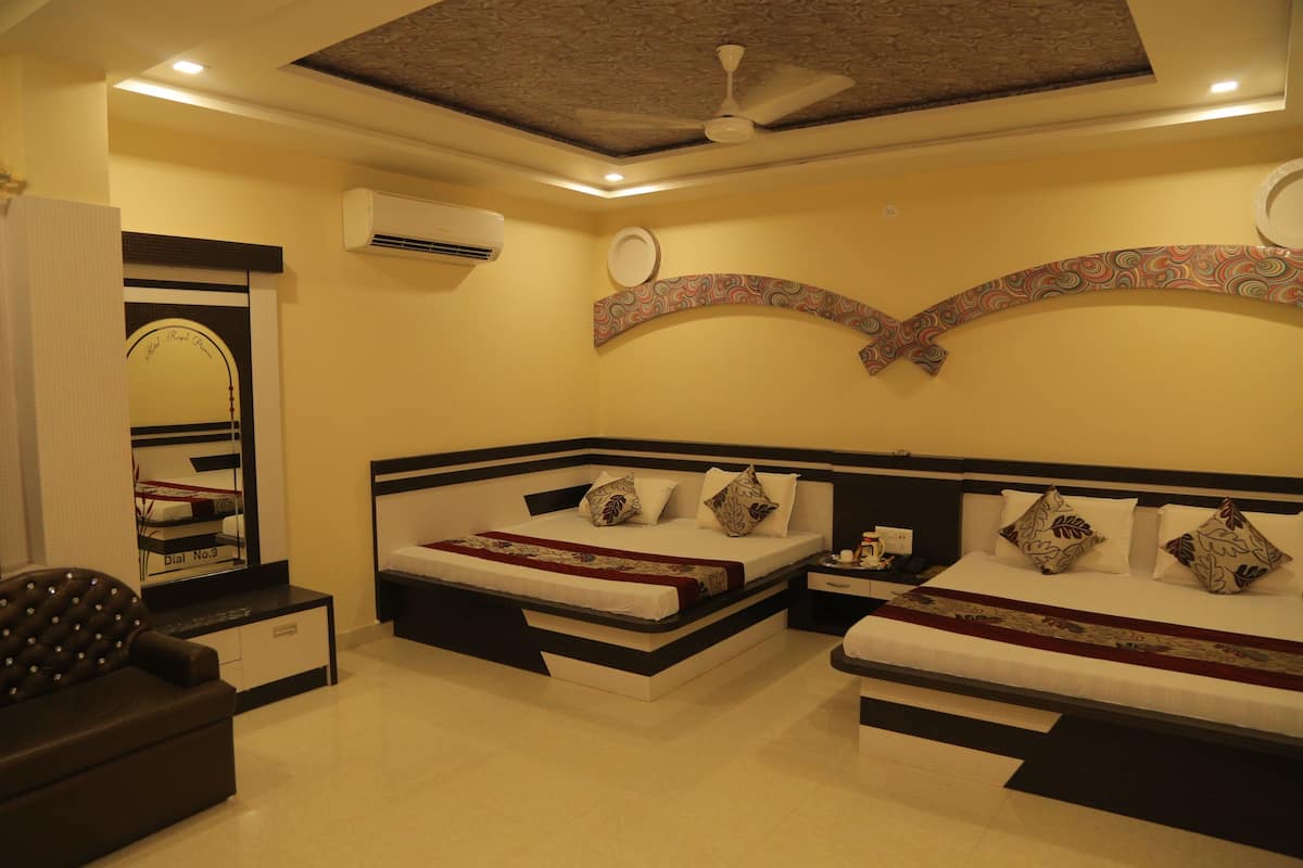 A hotel room with two beds, a sofa, a mirror, and a ceiling fan.