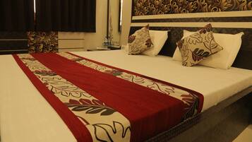 A hotel room with a neatly made bed, a red and white patterned bedspread, and a decorative headboard.