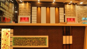 Un área de recepción con pared de piedra, un panel de pared con diseño y un cartel que indica un descuento del 10% S.C. EXTRA.