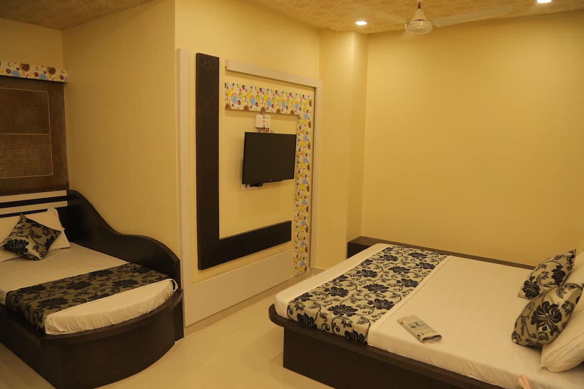 A hotel room with two beds, a television mounted on the wall, and a ceiling fan.