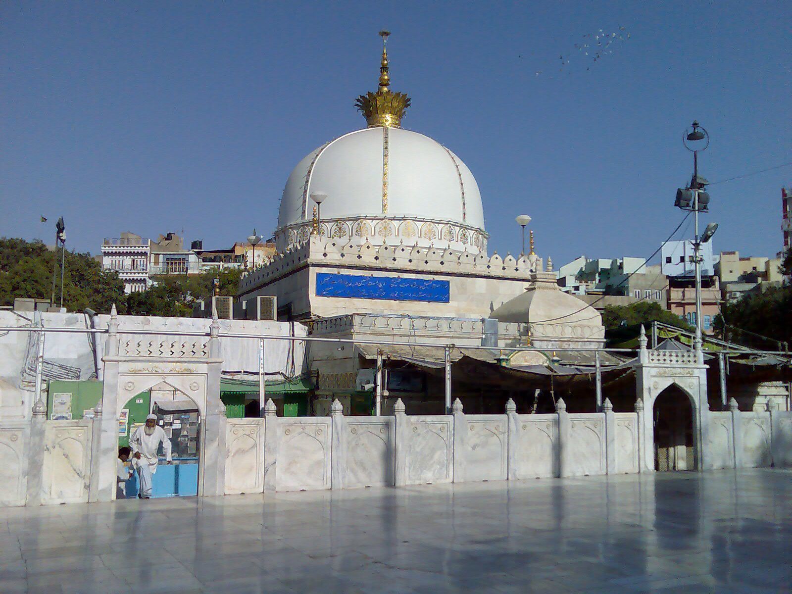 A large white dome with a golden finial, surrounded by a white wall with decorative elements.