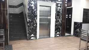 Un moderno ascensor con detalles metálicos, flanqueado por paredes de mármol con patrones geométricos.