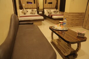 Habitación de hotel con sofá, dos camas con cabeceras, una mesa de madera con una bandeja de objetos y un espejo en la pared.
