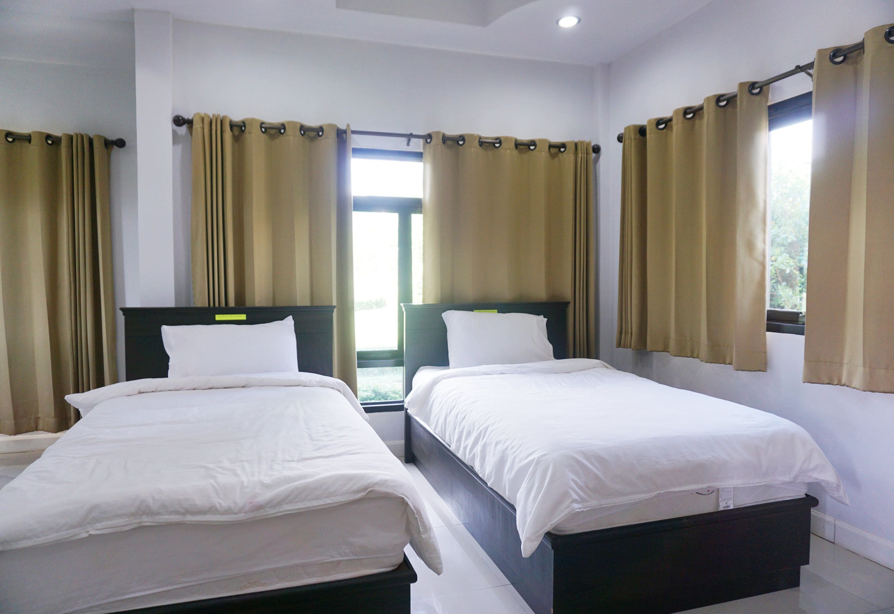 Una habitación de hotel con dos camas individuales, una ventana con cortinas y vistas al exterior.