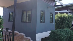 Una casa moderna con un porche cubierto, un pequeño jardín delantero y cielo despejado.